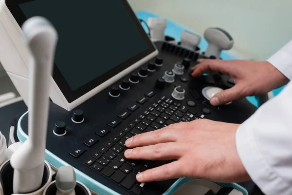 Vista recortada do médico que opera a máquina moderna do ultrassom com tela em branco — Fotografia de Stock