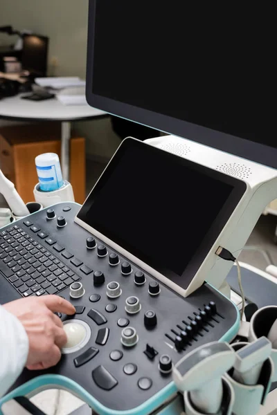Vue partielle du médecin opérant une machine à ultrasons moderne avec de grands moniteurs — Photo de stock