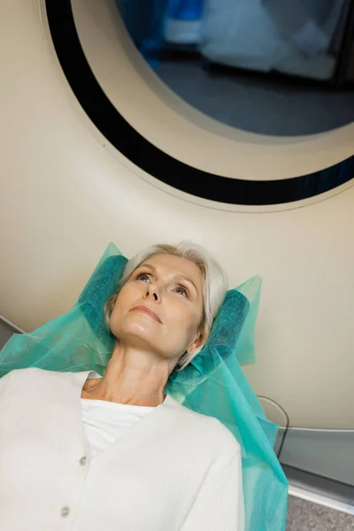 Vue grand angle de la femme blonde couché pendant les diagnostics sur ct scanner à l'hôpital — Photo de stock