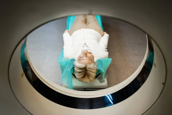 Высокий угол обзора зрелой женщины с закрытыми глазами, лежащей во время диагностики на КТ сканере — стоковое фото