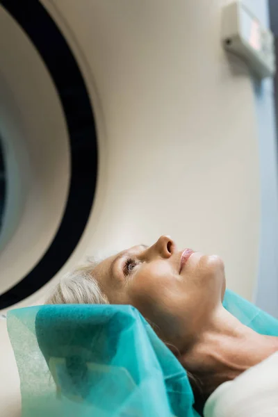 Bastante mujer de mediana edad haciendo la exploración en la máquina de tomografía computarizada - foto de stock