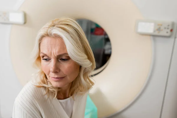 Preocupado mulher de meia idade perto de máquina de tomografia computadorizada na clínica — Fotografia de Stock