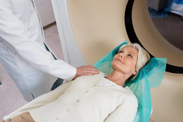 Donna sorridente guardando radiologo toccare la spalla prima della scansione in macchina tomografia computerizzata — Foto stock