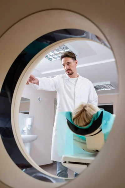 Doctor in white coat operating computed tomography machine during examination of woman — Stock Photo