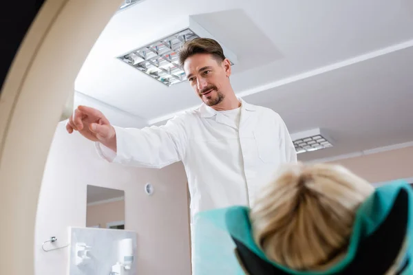 Radiologue brune en manteau blanc opérant scanner tomodensitométrie près du patient — Photo de stock