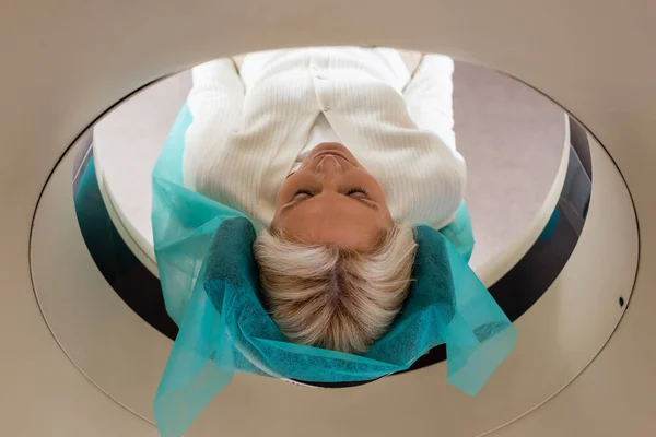 Bonita mulher loira com olhos fechados fazendo exame em tomografia computadorizada scanner — Fotografia de Stock