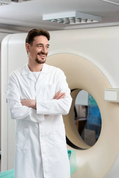 Усміхнений радіолог стоїть біля комп'ютерного томографічного сканера і дивиться геть — стокове фото