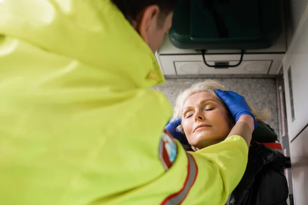 Vue en angle élevé du contrôle paramédical flou d'un patient mature dans un véhicule d'urgence — Photo de stock