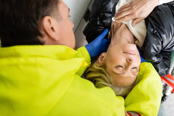 Vista superior de paramédico ayudando a la mujer de mediana edad en el vehículo de emergencia - foto de stock