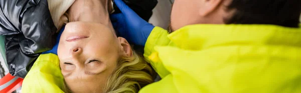 Вид сверху на парамедика в латексных перчатках, оказывающего первую помощь женщине средних лет, баннер — стоковое фото