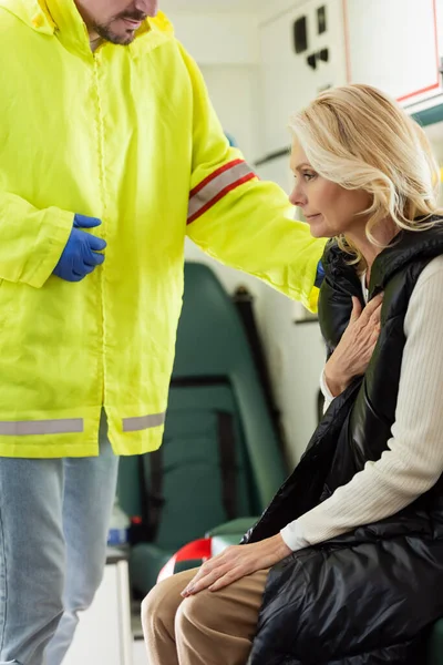 Ambulancier en uniforme apaisant femme mûre dans un véhicule d'urgence — Photo de stock