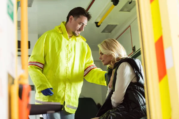 Paramedic calming sick middle aged woman in emergency vehicle — Stock Photo