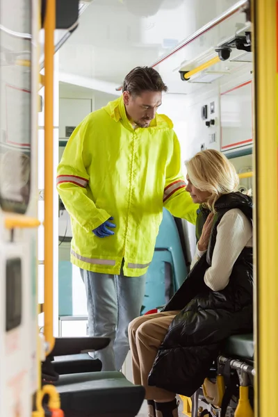 Paramédico de uniforme a olhar para o doente doente no veículo de emergência — Fotografia de Stock
