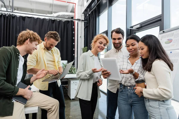 Multiethnische Geschäftskollegen mit Laptop und digitalem Tablet im Gespräch während eines Meetings im Büro — Stockfoto