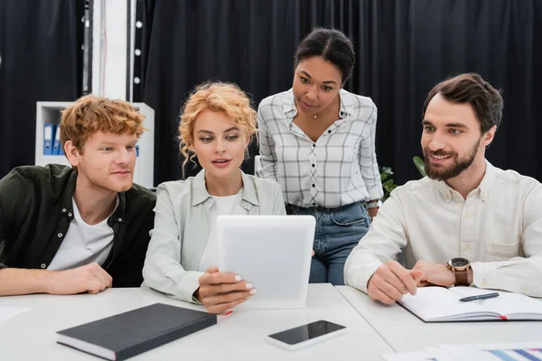 Blonde Geschäftsfrau hält digitales Tablet in der Hand, während sie mit interrassischem Team im Büro arbeitet — Stockfoto