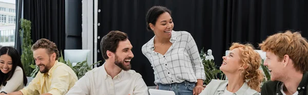 Multiracial businesswoman laughing with cheerful colleagues in meeting room, banner — Stock Photo