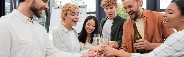 Радісні міжрасові менеджери тости з шампанським на корпоративній вечірці в офісі, банер — стокове фото