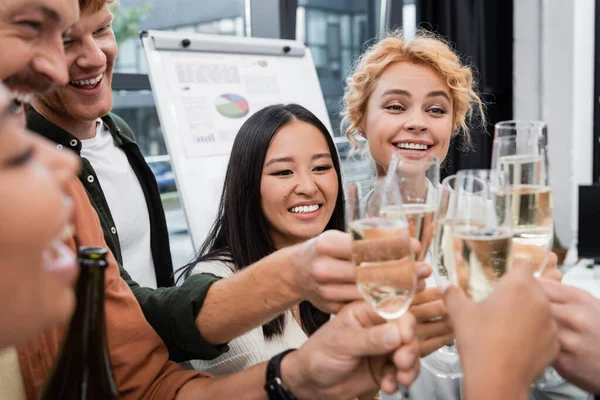 Multikulturelle Geschäftsleute klirren mit verschwommenen Champagnergläsern im Büro — Stockfoto