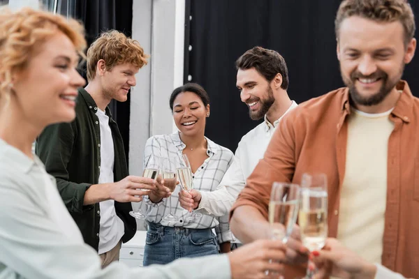 Sorridente interracial negócios pessoas clinking copos de champanhe durante o partido corporativo no escritório — Fotografia de Stock