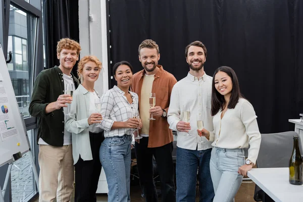 Multicultural business people holding glasses of champagne in office — Stock Photo