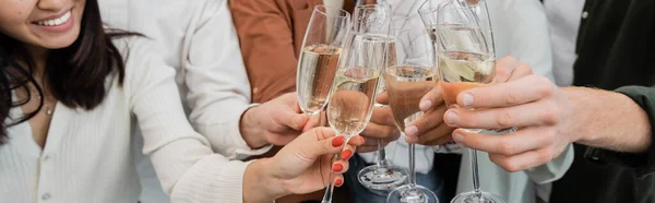 Cropped view of interracial business people clinking glasses of champagne in office, banner — Stock Photo