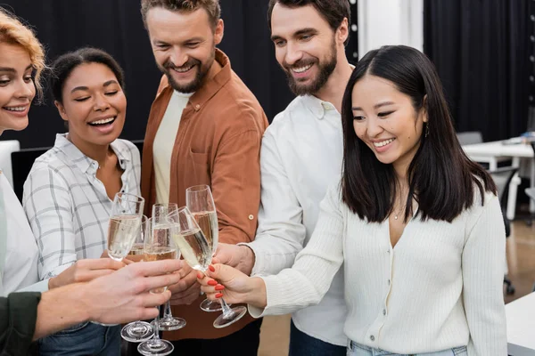 Усміхнена азіатська бізнес-леді смердить шампанське з багатоетнічними колегами в офісі — стокове фото