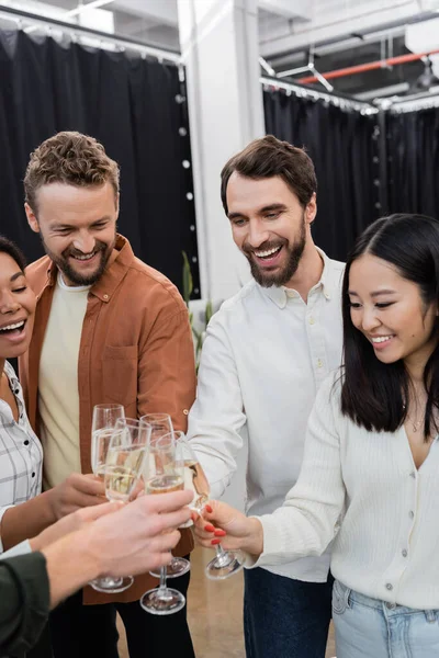 Alegre gente de negocios interracial tintineando champán durante la fiesta corporativa - foto de stock