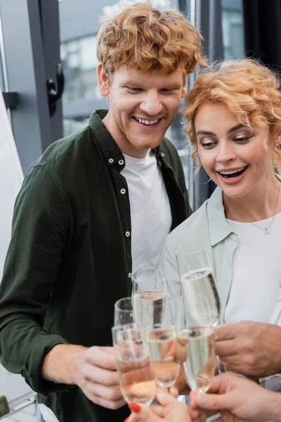 Smiling redhead businessman in casual clothes clinking champagne with colleagues in office — Stock Photo