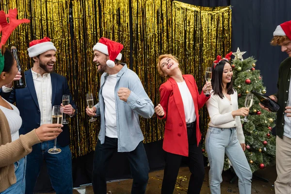 Багатонаціональні ділові люди з шампанським танцюють під час святкування Різдва в офісі — Stock Photo