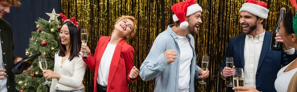 Allegri uomini d'affari interrazziale con champagne ballare e parlare durante la celebrazione di Natale, striscione — Foto stock