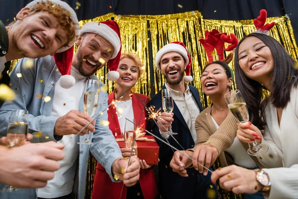 Niedriger Blickwinkel auf multiethnische Geschäftsleute mit Wunderkerzen und Champagner während der Neujahrsparty im Amt — Stockfoto