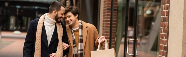 Alegre gay casal no moderno roupa andando com compras sacos no cidade, banner — Fotografia de Stock