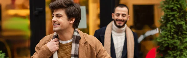 Happy and stylish gay man looking away near boyfriend on blurred background, banner — Stock Photo