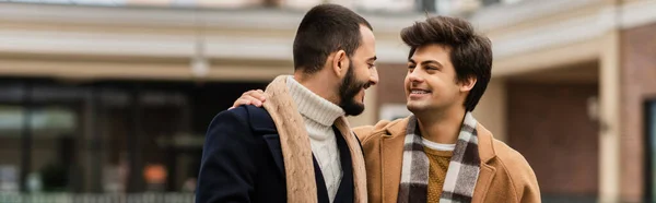 Happy gay couple in stylish outfits looking at each other outdoors, banner — Stock Photo