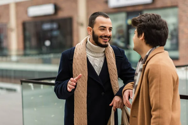 Cheerful bearded gay man in trendy clothes talking to boyfriend on city street — Stock Photo
