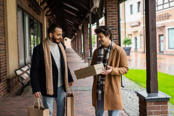 Jeune gay homme regardant shoebox près barbu copain avec shopping sacs — Photo de stock