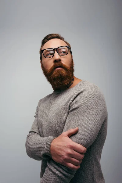Portrait of stylish bearded man in jumper and eyeglasses looking away isolated on grey — Stock Photo