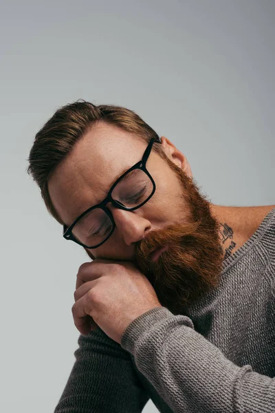 Homme barbu à lunettes posant les yeux fermés isolé sur gris — Photo de stock
