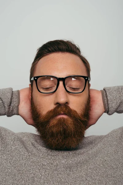 Portrait of bearded man in eyeglasses touching back of head isolated on grey — Stock Photo