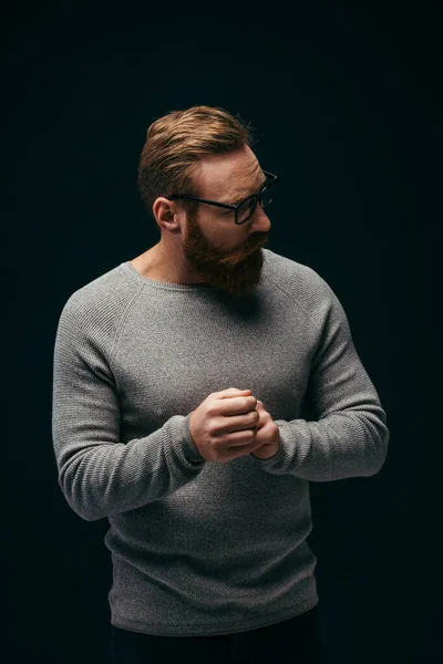 Стильний бородатий чоловік в окулярах дивиться ізольовано на чорному — стокове фото