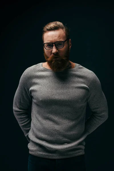 Portrait man in eyeglasses and grey jumper looking at camera isolated on black — Stock Photo