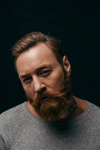 Portrait of bearded man in grey jumper looking at camera isolated on black — Stock Photo
