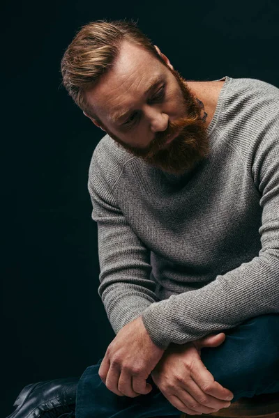 Bearded man in long sleeve looking away while posing isolated on black — Stock Photo