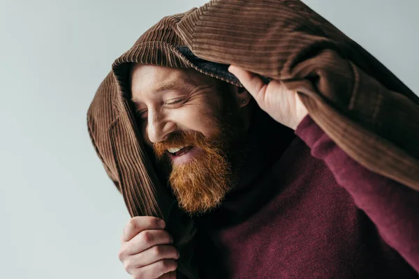 Счастливый мужчина с закрытыми глазами и коричневым блейзером на голове, улыбающийся изолированно на сером — стоковое фото