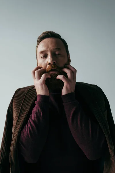 Homem de gola alta e blazer arranhando barba isolada em cinza — Fotografia de Stock