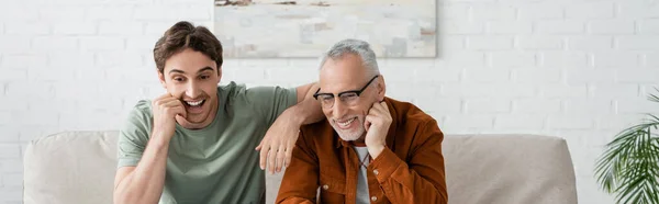 Cheerful young man smiling with bearded and mature father in eyeglasses, banner — Stock Photo