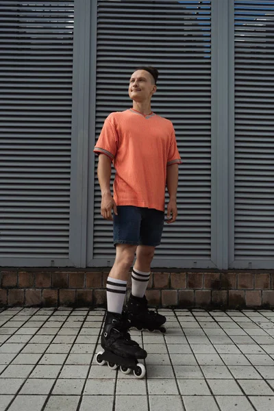 Молодий чоловік у повсякденному одязі та роликових ковзанах стоїть на міській вулиці — стокове фото
