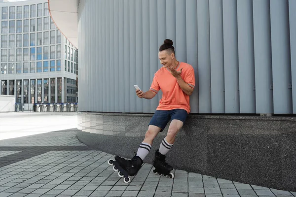 Lächelnder Mann auf Rollschuhen mit Videoanruf auf Stadtstraße — Stockfoto