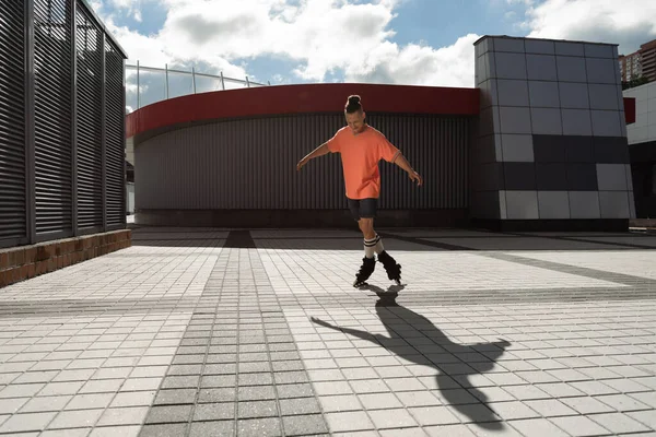 Jeune homme en patins à roulettes patinant près de bâtiments dans la rue urbaine — Photo de stock