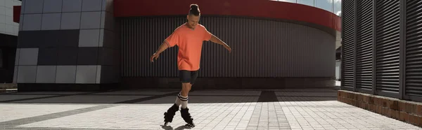 Giovane in pantaloncini e t-shirt pattinaggio a rotelle sulla strada urbana di giorno, striscione — Foto stock